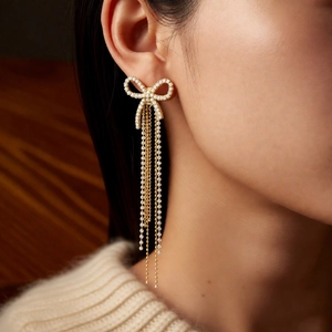 Close-up of elegant 18k gold-plated bow earrings with long pearl and tassel fringes
