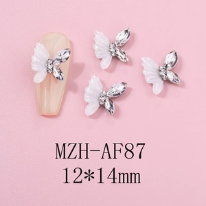 Macro detail of white resin butterfly nail charms with rhinestones on a nude nail tip