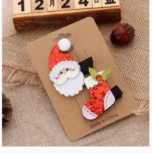 Detailed view of glittery Christmas hair clips with Santa and red sock designs on card