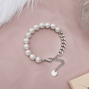 Detailed close-up of a silver beaded chain bracelet with lava texture on a soft background