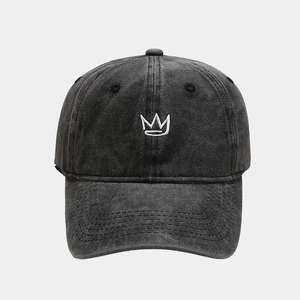 Detail of white crown embroidery on vintage washed dark grey denim baseball cap