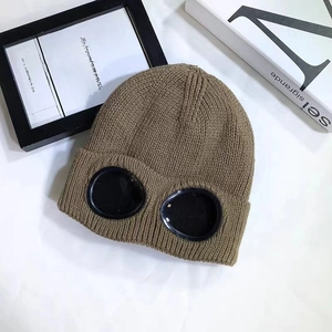 Detail of dark brown knit beanie featuring integrated black goggles and thick texture