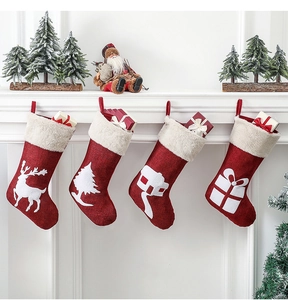 Hanging red plush Christmas stockings with reindeer and tree patterns on white fireplace