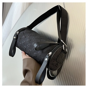 Detailed macro view of the black cylindrical crossbody bag with pleated texture finish