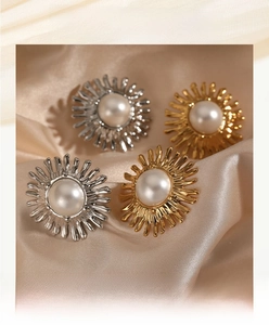 Detailed shot of sunflower pearl earrings in gold and silver on silk fabric