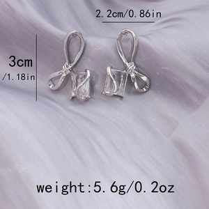 Silver bow knot earrings with rectangular crystal detail and product size measurements