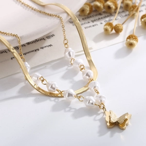 Detailed close-up of golden double-layer butterfly pendant with snake chain and pearls