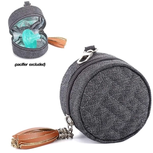 Detail of round grey pacifier holder with brown leather tassel and metal carabiner hook