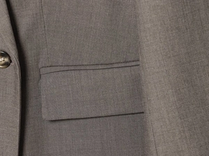 Detail of taupe fabric texture and flap pocket design on a casual double-breasted suit
