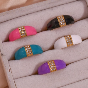 Macro shot of colorful enamel 18K gold rings with diamonds in a velvet jewelry box