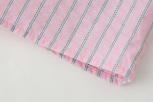 Détail du tissu en coton à rayures roses et bleues avec couture soignée sur le poignet