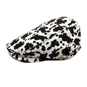 Stylish black and white cow print newsboy cap with vintage gold buckles on side