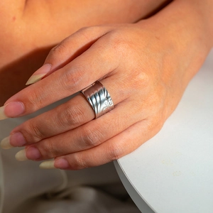 Close-up of silver wide band stainless steel ring with intricate floral engraving