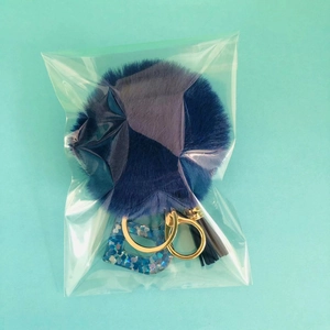 Detail view of dark blue pompom keychain with glitter letter D and gold lobster clasp