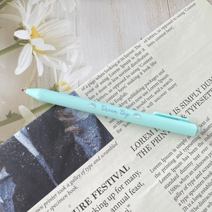 Detail of light blue retractable gel pen with Dream Big quote on a vintage book page