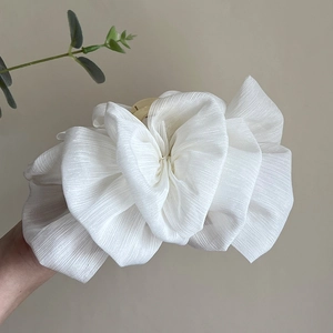Close-up of white oversized mesh bow hair claw clip made of pleated fabric material