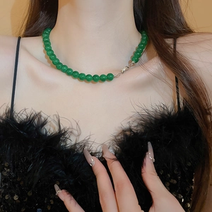 Détail du collier de perles en verre vert émeraude avec fermoir en métal sur le cou