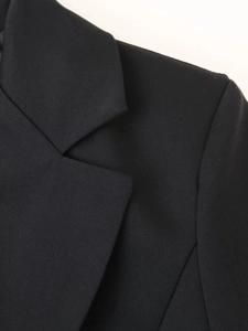 Détail de la robe noire à col en V montrant le tissu en sergé et la ligne d'épaule nette
