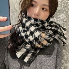 Close-up of thick knit gradient plaid scarf in black, white, and beige with fringe details