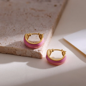 Close-up of French vintage pink enamel gold hoop earrings on beige marble stone