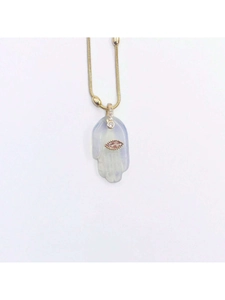 Detalle de un colgante de mano de Hamsa con ojo turco rosa en una cadena dorada.