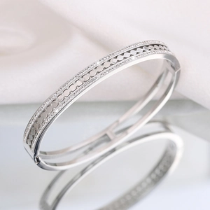 Close-up of elegant silver stainless steel hollow bangle on a reflective surface