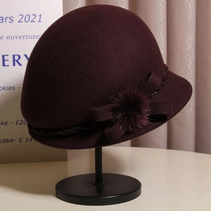 Detail of wool cloche hat in burgundy featuring an elegant bow and soft mink fur ball
