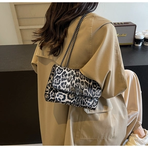 Detailansicht einer stilvollen Schultertasche mit Leopardenmuster und Goldkette im Café