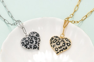 18K gold-plated heart leopard print necklaces set on a textured white shell tray