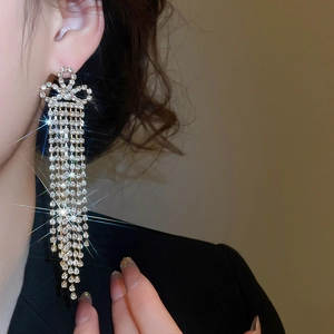 Close-up of sparkling bow tassel earrings with micro-set rhinestones on a female model