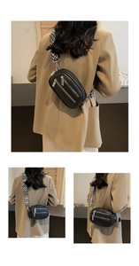 Detail der schwarzen Brusttasche aus genarbtem Leder mit silbernen Zippern und Muster-Gurt