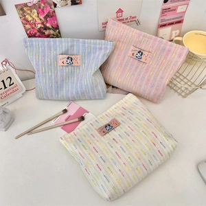 Three colorful woven cosmetic bags with cartoon patches on a desk with decor