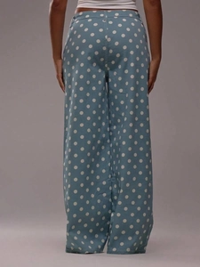 Detail shot of blue wide-leg denim pants featuring white polka dots from the back view