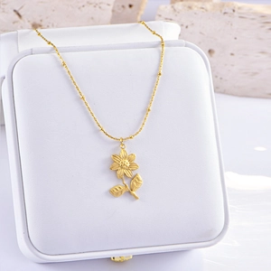 Elegant gold necklace with floral pendant on a white jewelry box, natural nature-inspired style