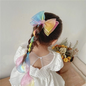 Rainbow ribbon hairclip with long braid and large bow detail worn by a little girl