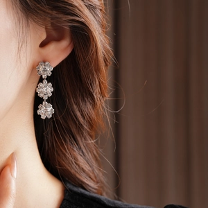 Macro shot of elegant floral cluster stud earrings with sparkling stones on model