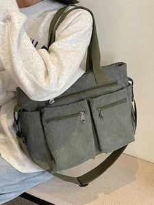 Army green corduroy crossbody bag with multiple zip pockets shown in a natural outdoor style