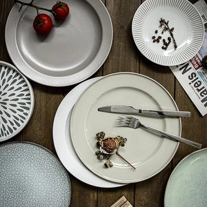 Rustic round ceramic dinner plates set in various colors on dark wood tabletop