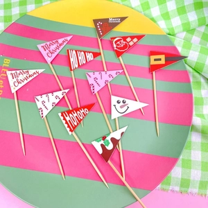 Detail of colorful paper Christmas cake toppers with Merry Christmas text on a festive plate