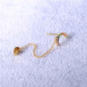 Detail of S925 silver gold chain earring with rainbow zircon inlay on soft fabric