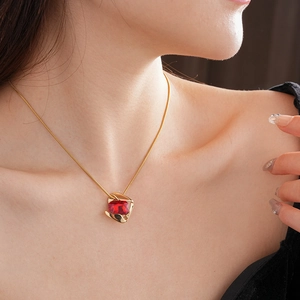 Macro shot of gold necklace featuring a geometric pendant with a square red gemstone