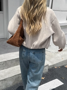 Outdoor street style view of the back of a beige long-sleeved casual jacket with brown bag