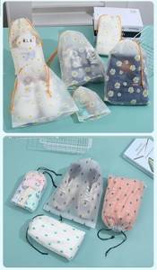 Detail of frosted drawstring storage bags with daisy and cactus prints for travel packing