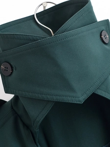 Detail of dark green trench coat collar with black button and fine twill fabric texture