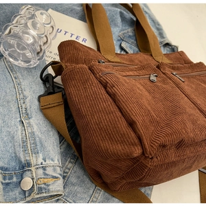 Detail shot of brown corduroy shoulder bag with multi-zipper pockets and adjustable strap