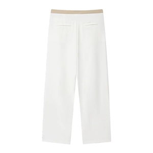 Detail of white wide-leg trousers featuring a beige patchwork waistband in suit fabric