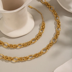 Detail of 18K gold-plated knotted link necklaces draped on a white ceramic vase