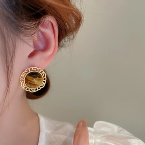 Close-up of vintage faux tiger eye earring with golden lace detail on model ear