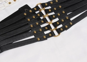 Detail of black faux leather corset belt with crocodile pattern and gold metal rings