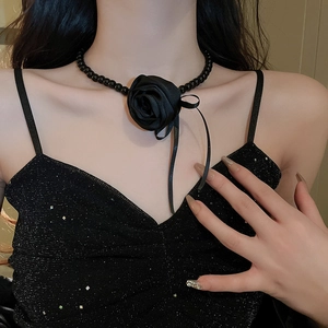 Detail of a black fabric rose choker with ribbon bow and beads on a model